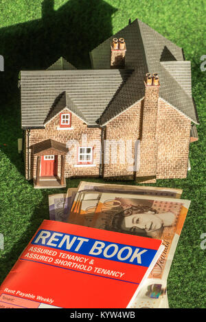 Model house, rent book (for assured shorthold tenancy, in England and Wales) and pounds sterling notes. General concept of renting / letting a home. Stock Photo