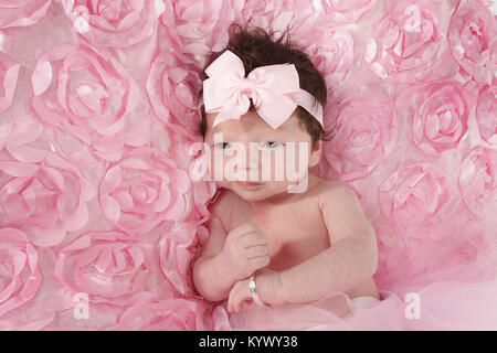 3 week old baby girl with lots of dark hair in too-too laying on rug Stock Photo