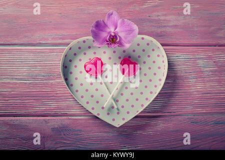 Gift box in heart shape and candy on pink background Stock Photo