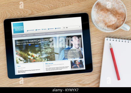 The American Express website on an iPad tablet, on a wooden table beside a notepad, pencil and cup of coffee (Editorial only) Stock Photo