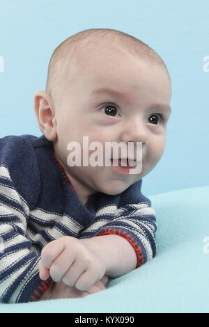 12 week old baby boy exploring on soft blue blanket Stock Photo