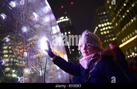 A girl touches the Sonic Light Bubble, an installation presented at the Canary Wharf winter lights festival, as sculptures, structures and installations are presented in different forms of light technology.