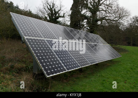 Solar cells in green field with trees in the background. Alternative renewable energy concept Stock Photo