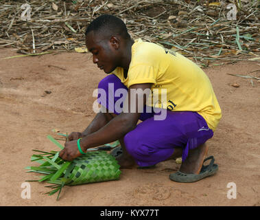Man weaving a basket with palm tree leaves, Zanzibar, Tanzania. Stock Photo
