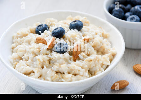 Oatmeal coconut porridge with blueberries and almonds in white bowl. Closeup view. Dietetic food, healthy eating, healthy food concept Stock Photo