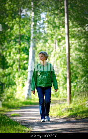 Middle aged woman taking a carefree walk in the forest Stock Photo
