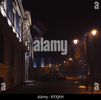 Small Balkan town in winter, at night, with fog and some passerby. Stock Photo