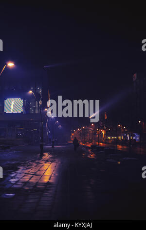 Small Balkan town in winter, at night, with fog and some passerby. Stock Photo