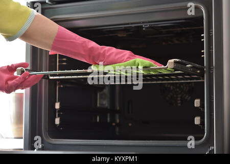 Cleaning the oven. Woman's hand in household cleaning gloves cleans oven inside. Clean oven in kitchen. Stock Photo