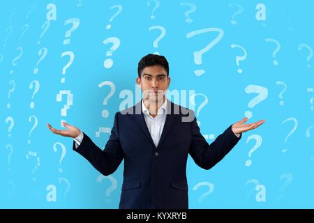 Man shrugging in front of a blue background with question marks pattern Stock Photo