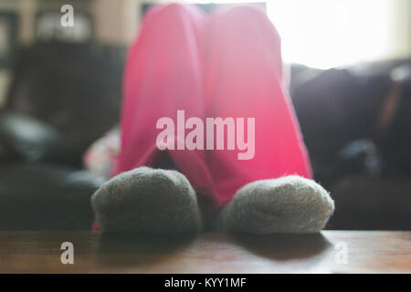 Low section of teenage girl wearing socks while resting legs on table at home Stock Photo