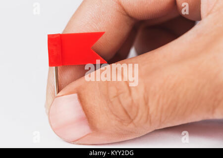 Isolated male hand with plastic red flags pin Stock Photo