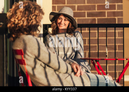 Smiling businesswoman looking at female colleague while sitting in hotel balcony Stock Photo