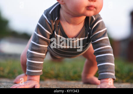 Low section of baby boy trying to stand at backyard Stock Photo