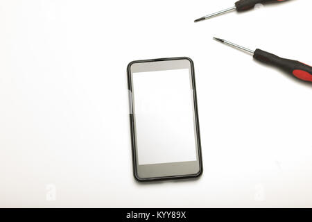 Studio shot high-angle view close-up of precision screwdrivers and a smartphone in a concept of screen replacement, repairs and maintenance over white Stock Photo