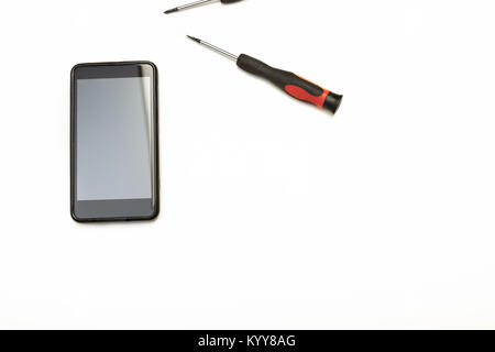 Studio shot high-angle view close-up of precision screwdrivers and a smartphone in a concept of screen replacement, repairs and maintenance over white Stock Photo