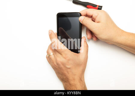 Man replacing a smartphone screen holding the mobile phone in his hand with a screwdriver alongside in a concept of DIY repairs and maintenance Stock Photo