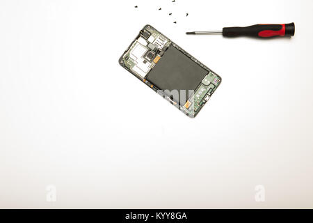 Studio shot high-angle view close-up of precision screwdriver and disassembled mobile phone in a concept of screen replacement, repairs and maintenanc Stock Photo