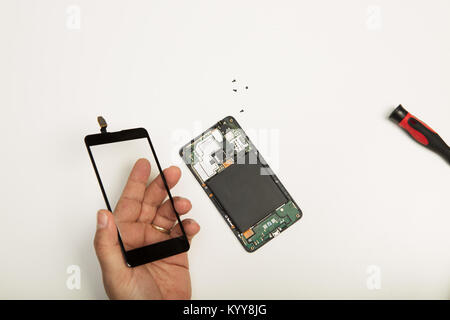 Man removing the screen of a smartphone and holding it in his hand in a concept of DIY repairs and maintenance over white with copy space Stock Photo