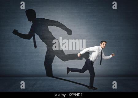 business man runs but his shadow goes in another direction Stock Photo