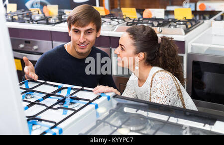 Ordinary young couple choosing gas hobs in hypermarket and smiling Stock Photo