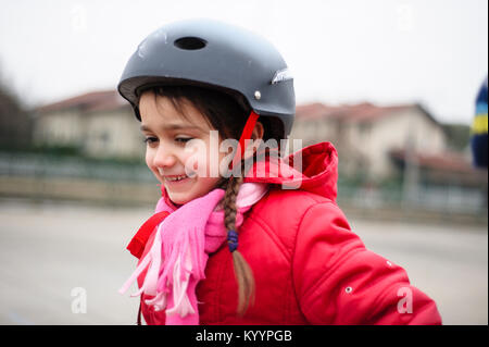 little girl learns to skate with rollerblading at the basketball court on a winter day Stock Photo