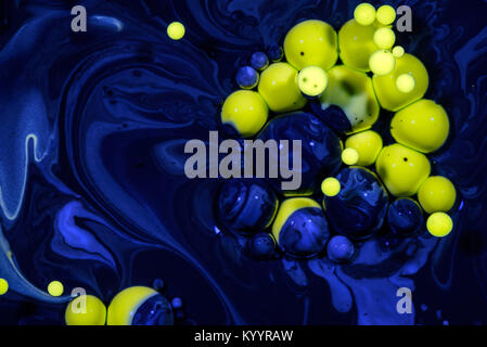 Yellow drops of oil suspended in blue chemical oil slick creating an abstract between nature and a polluted hazardous environment Stock Photo