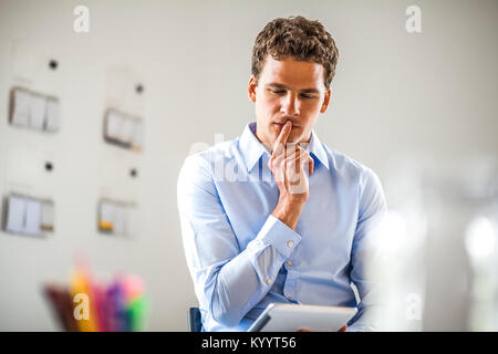 Thoughtful businessman using digital tablet in office Stock Photo