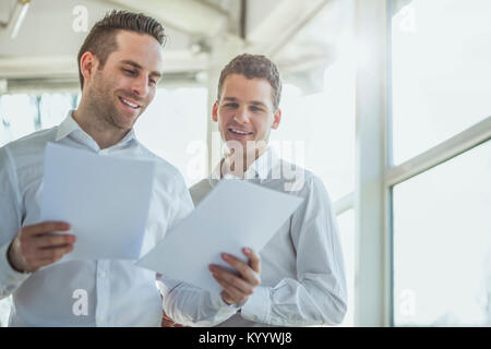 Smiling young businessmen reviewing documents in office Stock Photo
