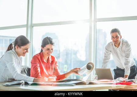 Young architects working on blueprint at desk in office Stock Photo