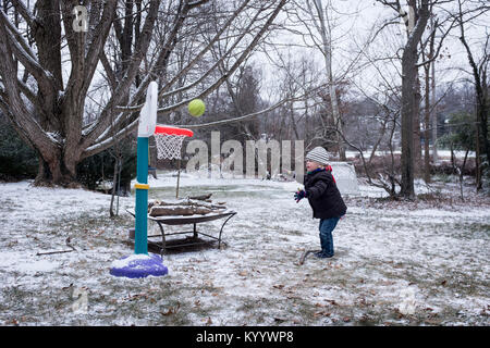 Little boy plays basketball in the snow in McLean, Virginia Stock Photo