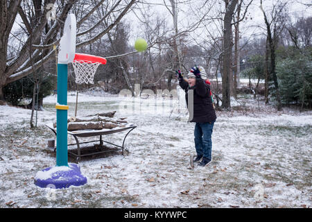 Little boy plays basketball in the snow in McLean, Virginia Stock Photo