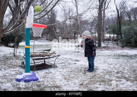 Little boy plays basketball in the snow in McLean, Virginia Stock Photo