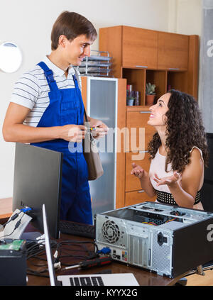 Happy young woman and PC engineer repairing her broken computer Stock Photo
