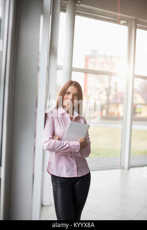 Portrait of confident young businesswoman holding digital tablet in office Stock Photo