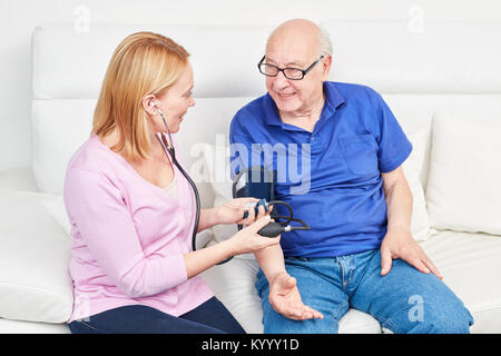 Young woman makes blood pressure measurement at a senior in home nursing Stock Photo