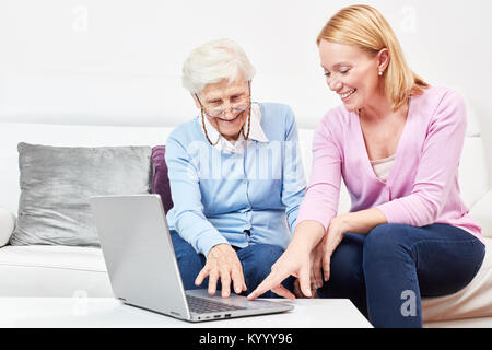Junge Frau erklärt einer Seniorin einen Laptop Computer und das Internet Stock Photo