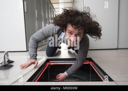 young IT engineer connecting cables in server room at modern data center Stock Photo