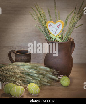 Easters still life of painted eggs, raw wheat and clayware. Rustic style. Stock Photo