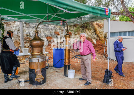 Arsos Village, Cyprus - October 8, 2017: Man toasting with Zivania from a working still at a village festival. Stock Photo