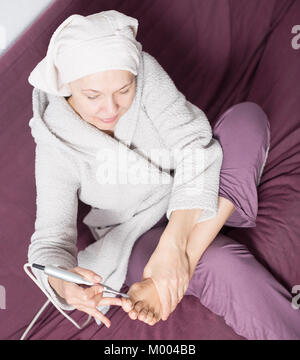 Senior woman starting feet pedicuring with special devices at home Stock Photo