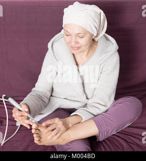 Senior woman starting feet pedicuring with special devices at home Stock Photo