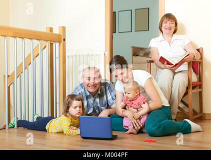 Happy friendly family of three generations with laptop  in living room at home Stock Photo