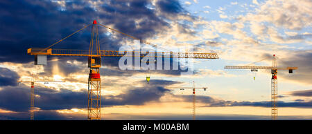 Construction site. Tower cranes on cloudy sky at sunset or sunrise background. 3d illustration Stock Photo
