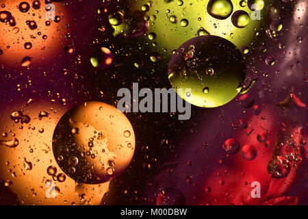 Colorful and bright background with circle oil drops that reflect yellow, orange, purple, green and red color. Color spots intentionally unfocused. Co Stock Photo