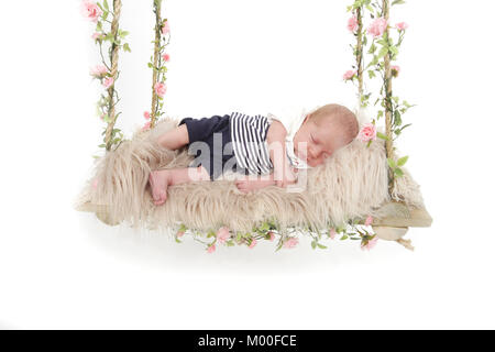 beautiful 4 week old baby boy sleeping on swing, nap time Stock Photo