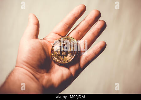 Close up to hand holding Bitcoin coin over bright background Stock Photo