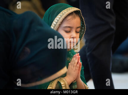 A little girl prays with her eyes closed, kneeling in front of the ·Guru Granth Sahib·, the Sikh holy book before entering the Gurdwara Sikh temple in Frankfurt am Main, Germany, 7 January 2018. The Sikh community in Hesse is the largest in Europe - Up to 2000 people can come together for weekend prayers. Photo: Boris Roessler/dpa Stock Photo