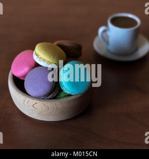 Macaroons in a bowl  and cup of coffee on the table, close up Stock Photo