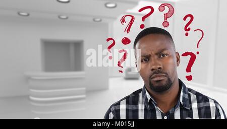 Confused man in a white office with red question marks Stock Photo